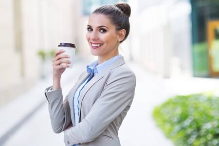 Businesswoman holding disposable cup outdoorsの写真素材
