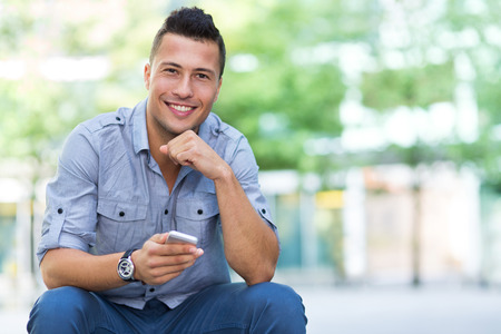 Young man with smartphone outdoorsの写真素材