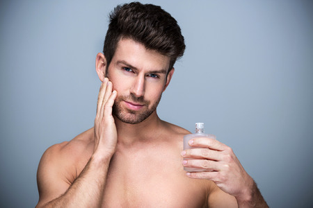 Man holding up bottle of perfumeの写真素材