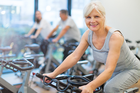 Confident seniors on exercise bikes in spinning class at the gymの写真素材