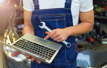 Mechanic Using Laptop While Examining Car Engineの写真素材