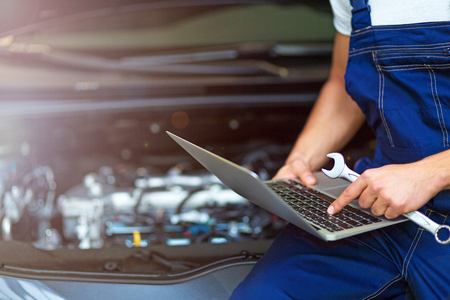 Mechanic Using Laptop While Examining Car Engineの写真素材