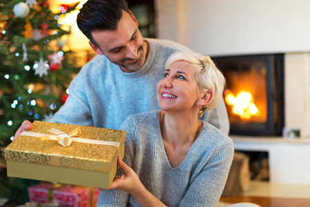Happy Couple with Christmas Gift at Homeの写真素材