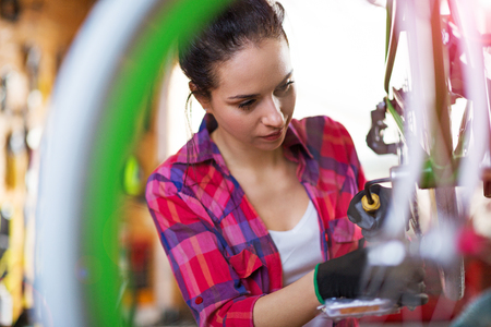 Confident young woman working in a bicycle repair shopの写真素材