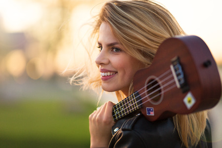 Woman carrying guitar at sunset