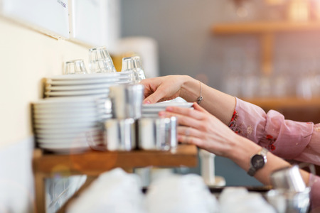 Close up of woman putting clean dishes to dryの写真素材