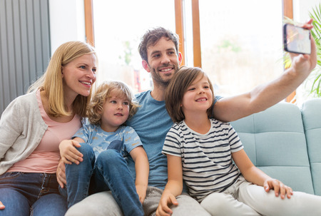 Family taking selfie while sitting on sofa at homeの写真素材