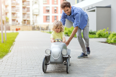 Father helping his son to drive a toy peddle carの写真素材