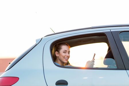 Young woman with smartphone on the back seat of a carの写真素材