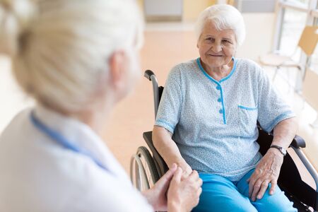 Senior woman in wheelchair with nurse in hospital