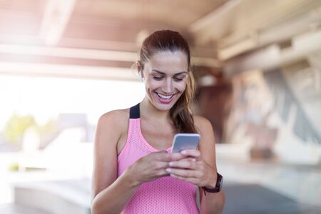 Female runner using smartphone in a urban city areaの写真素材