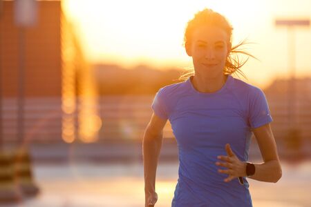 Young woman running on parking level in the city at sunset