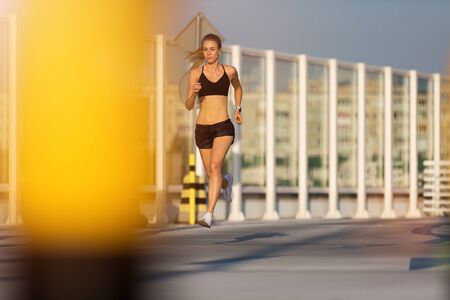 Young woman jogging in urban area at sunset