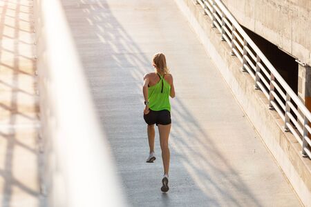 Young woman jogging in urban area at sunset