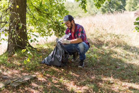 Young man picking up litter in his local park