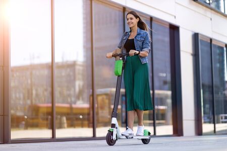 Happy woman riding on an e-scooterの写真素材