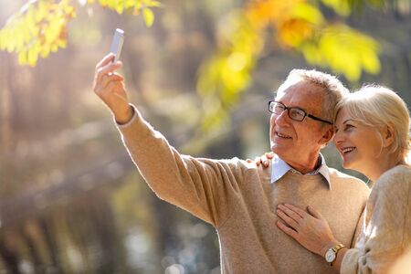 Happy senior couple in autumn parkの写真素材