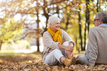 Elderly couple standing together in autumn parkの写真素材