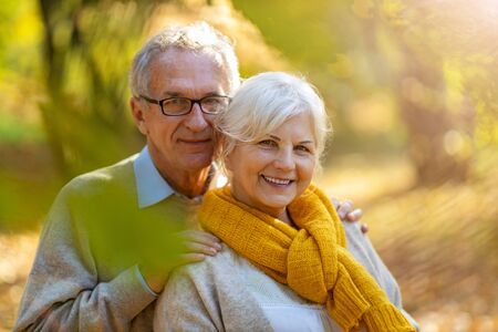 Elderly couple standing together in autumn parkの写真素材