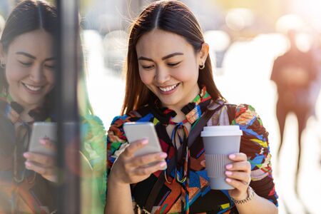 Attractive young woman with smartphone and coffee in the cityの写真素材