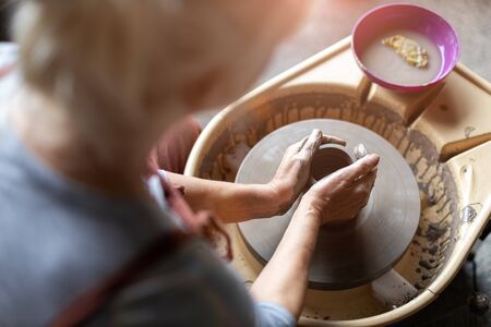 Hand made ceramics are formed by a mature woman on a potters wheelの写真素材