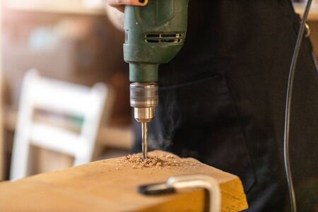 Young woman using electric drill in industrial workshop