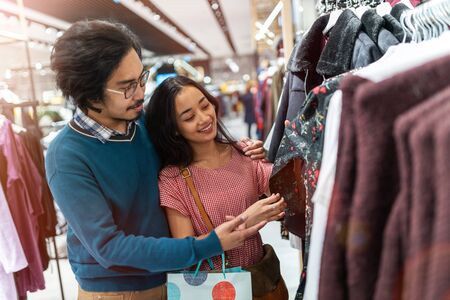 Happy young couple shopping for clothes in boutique