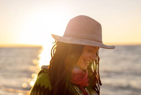 Young woman in a hat on the beach at sunsetの写真素材