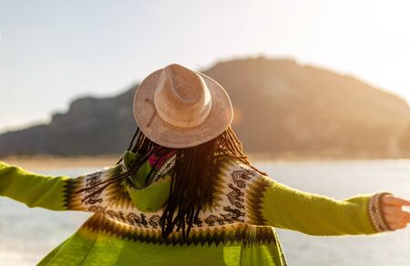 Rear view of young woman enjoying sunset on the beachの写真素材