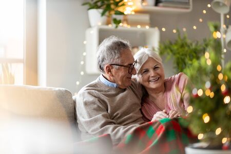 Senior couple sitting in the living room together during Christmasの写真素材