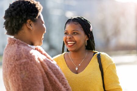 Beautiful happy girlfriends talking and smiling in cityの写真素材