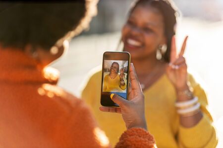 Happy girlfriends taking a photo whilst showing Victory sign with handの写真素材