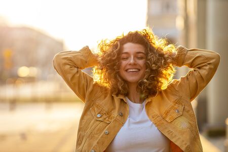 Portrait of young woman with curly hair in the cityの写真素材