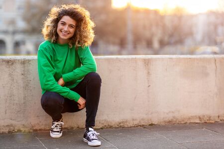 Portrait of young woman with curly hair in the cityの写真素材
