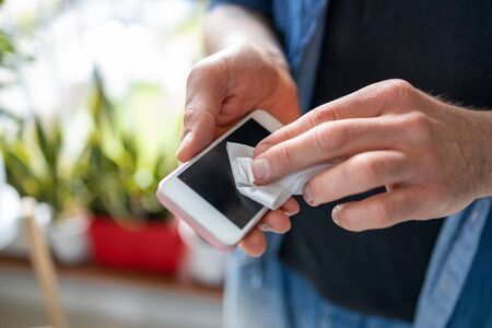 Man using a disinfection wipe on a phoneの写真素材