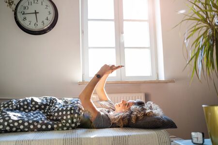 Young woman using smartphone in bed