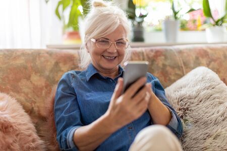 Senior woman using mobile phone at home