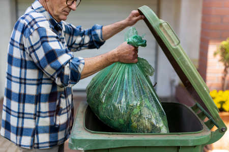 Senior man taking out garbage