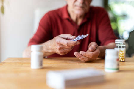 Senior man taking prescription medicine at homeの写真素材
