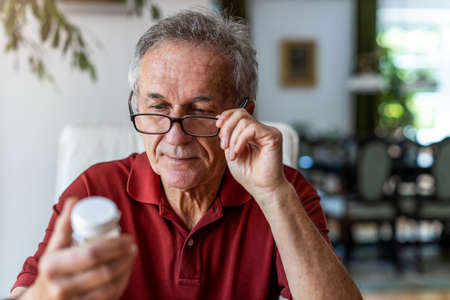 Senior man taking prescription medicine at homeの写真素材