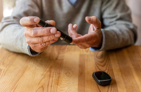 Mature Man Checking Blood Sugar Level With Glucometer