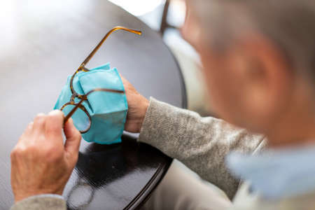 Senior man wiping eyeglasses with clothの写真素材