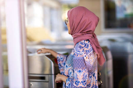 Muslim woman checking out at metro station using mobile phoneの写真素材