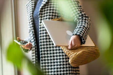 Unrecognizable female executive holding laptop and mobile phone