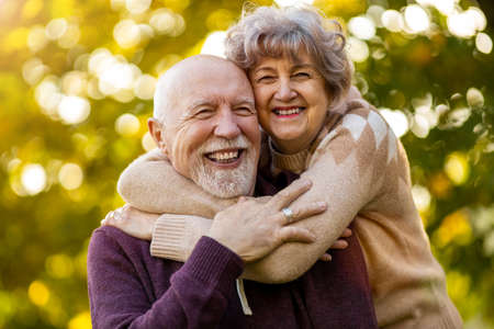 Happy senior couple spending time together in beautiful city park in autumn