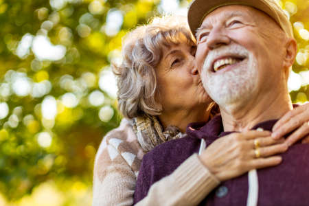 Happy senior couple spending time together in beautiful city park in autumn