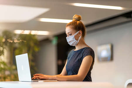 Businesswoman wearing protective face mask working in a modern office