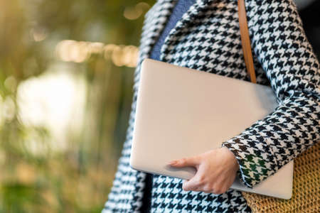 Unrecognizable woman with handbag and laptop