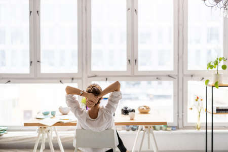 Rear view of young woman working on laptop in loft officeの写真素材
