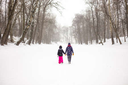 Mother and daughter walking through a winter parkの写真素材